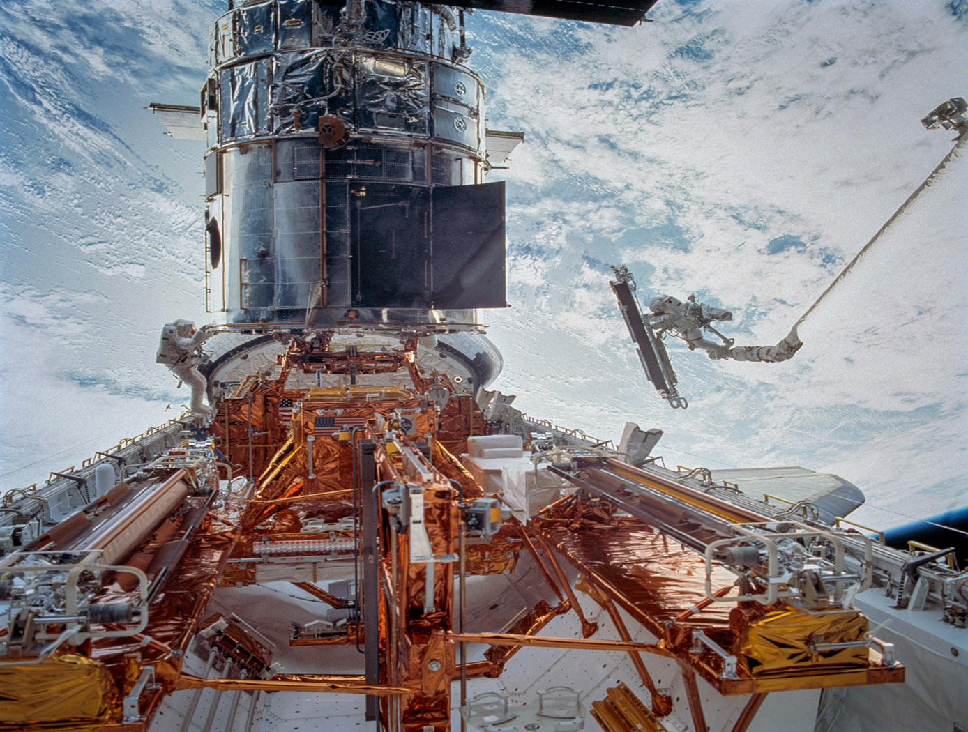 In celebration of the 25th anniversary of NASA's first space servicing mission to the Hubble Space Telescope, we are sharing this gallery of images from all five of the Hubble servicing missions. Astronauts serviced Hubble for the first time in December 1993. Including that trip, there have been five astronaut servicing missions to Hubble between 1993 and 2009. How did astronauts repair and service the Hubble Space Telescope more than 300 miles above the surface of the Earth? Watch Hubble astronauts as they discuss servicing from the innovative Robotics Operations Center: bit.ly/2EiiNTP STS109-713-003 (8 March 2002) --- Astronaut John M. Grunsfeld, STS-109 payload commander, anchored on the end of the Space Shuttle Columbias Remote Manipulator System (RMS) robotic arm, moves toward the giant Hubble Space Telescope (HST) temporarily hosted in the orbiters cargo bay. Astronaut Richard M. Linnehan works in tandem with Grunsfeld during this fifth and final session of extravehicular activity (EVA). Activities for the space walk centered around the Near-Infrared Camera and Multi-Object Spectrometer (NICMOS) to install a Cryogenic Cooler and its Cooling System Radiator.